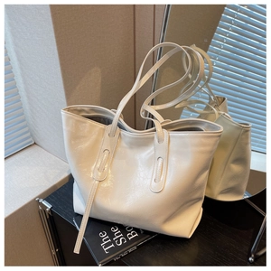 Macro detail of white glossy tote bag showing premium leather texture and long strap design