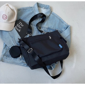 Detail of black canvas messenger bag with adjustable strap and small round coin purse