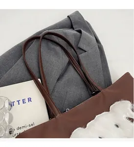 Vista plana del bolso tote marrón con parche de cachorro sobre blazer gris y libro