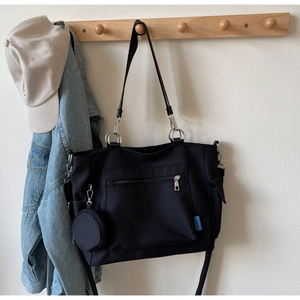 Detail of black oxford tote bag with round coin purse and adjustable strap on a hook