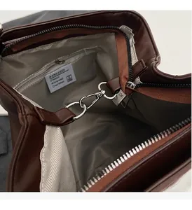 Detalle del interior del bolso de cuero marrón con forro de espiga y herrajes plateados
