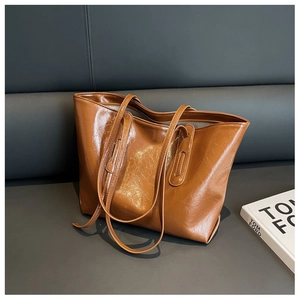 Detail of a brown glossy tote bag with crinkled texture on a luxury leather background