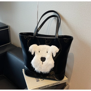 Détail d'un cabas en cuir verni noir avec un écusson de chien en peluche blanche