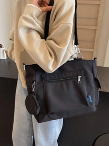 Large black nylon tote bag with front pocket and round coin purse shown on model