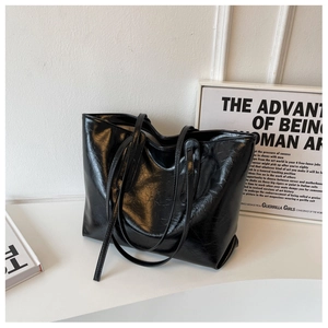 Detailed view of black oil wax leather tote bag with crinkled texture and glossy finish