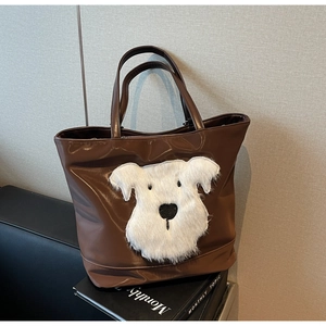 Détail d'un sac cabas marron foncé brillant avec un adorable écusson chien peluche