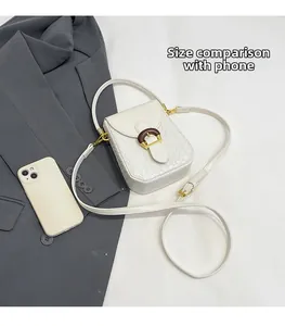White woven crossbody phone bag size comparison next to a gray blazer and a smartphone