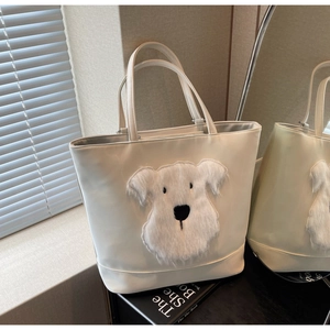Détail de l'écusson chien en peluche sur le grand sac cabas en similicuir blanc cassé