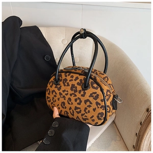 Detail der Handtasche mit Leopardenmuster, Wildleder-Haptik und schwarzen Handgriffen