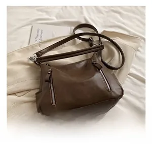 Detail view of brown vintage PU leather bag featuring silver zippers and adjustable straps