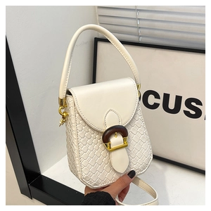 Close-up of cream woven crossbody bag with brown wooden buckle and gold hardware details