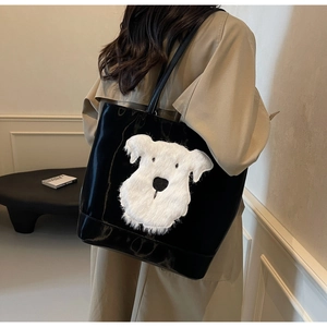 Détail d'un cabas noir brillant avec écusson chien en peluche blanche sur un trench-coat