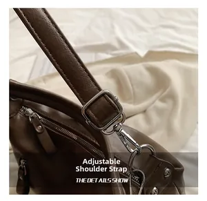 Detail of adjustable dark brown leather shoulder strap with silver metal buckle and hook
