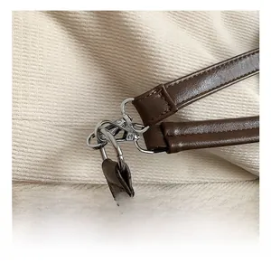 Detail of dark brown leather tote bag showing silver metal hook and fine stitching craftsmanship