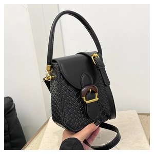 Detail showing woven texture and gold clasp on a black leather crossbody handbag