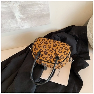 Detailansicht der Handtasche mit Leopardenmuster und schwarzen Griffen auf einem Mantel