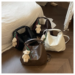 Detail view of large tote bags in four colors with cute teddy bear charms on wood floor