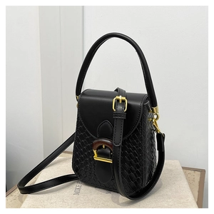 Detail of black woven texture handbag with vintage gold buckle and smooth leather flap