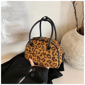 Detailansicht der Handtasche mit Leopardenmuster, runden schwarzen Griffen und Metallteilen