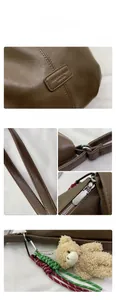 Detailed view of coffee tote bag with litchi texture, silver zipper and bear charm