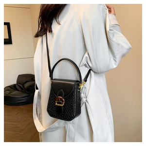 Detail view of black leather and woven bag featuring a vintage round buckle for women
