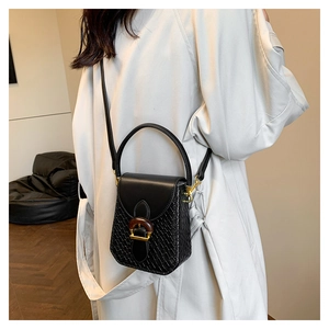 Detail of crossbody phone bag with woven leather texture and wooden clasp accent