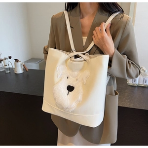 Détail de l'écusson chien en peluche sur un cabas blanc cassé avec doubles bretelles