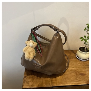 Macro detail of brown PU leather tote bag texture with plush bear and braided strap
