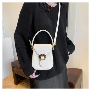 White croc-embossed mini crossbody bag with gold hardware shown on a model