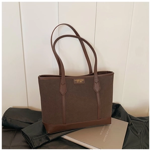 Close-up of brown frosted tote bag with leather trim and vintage brand logo detail