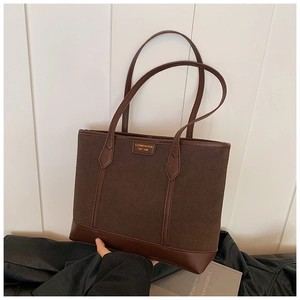 Detail view of large dark brown frosted tote bag with premium leather trim and gold brand tag