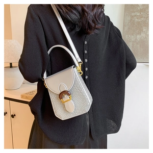 Detail view of silver embossed crossbody bag with wooden buckle and golden metal hardware