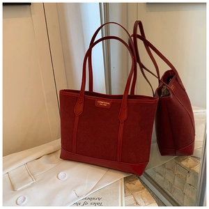 Detail of red matte leather tote bag featuring golden logo and stitched texture panels