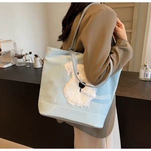 Détail du cabas bleu clair avec broderie de chiot en peluche dans un décor de café