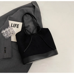 Detail of black matte tote bag with bow accent and material stitching on blazer background
