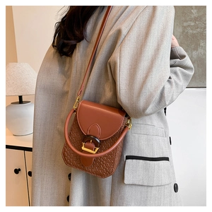 Brown woven leather mini crossbody bag with round handle and gold hardware on a model