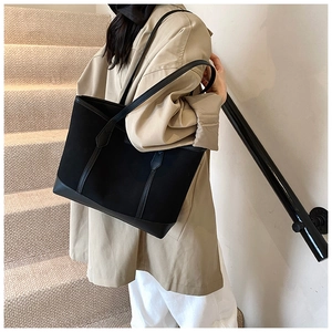 Detail of minimalist black canvas tote bag with leather straps on a female model