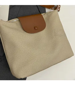 Detail of beige woven tote bag featuring brown leather flap and patterned shoulder strap