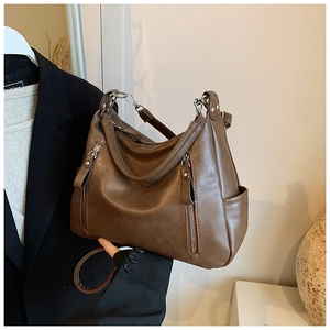 Detail view of vintage brown leather bag showing two vertical zippers and soft leather texture