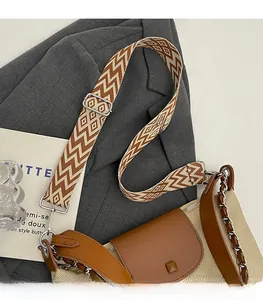 Detail of adjustable geometric patterned strap and metal chain on beige tote bag