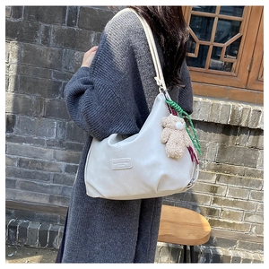 Detail of cream white PU leather tote with logo patch and brown plush bear charm