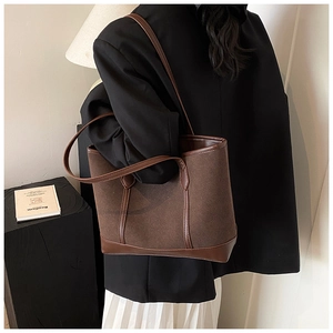 Detail of brown felt tote bag with leather trim worn over the shoulder by a model