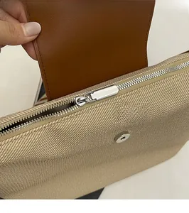 Detail of silver metal zipper and magnetic snap on a canvas and leather tote bag