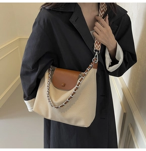 Detail of canvas tote with brown leather flap and stylish woven shoulder strap