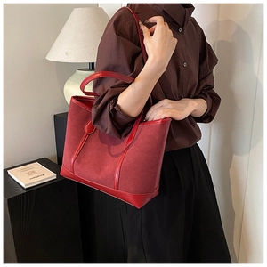 Detail of vintage burgundy tote bag in matte suede with leather trim shown on model