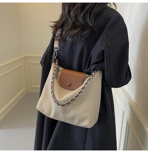 Detail of a beige canvas tote bag with brown leather flap and stylish checkered strap