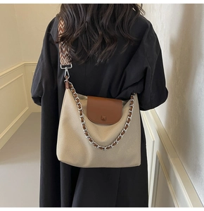 Detail of canvas tote bag with brown leather trim and jacquard strap shown on model