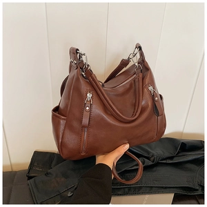 Detail of a brown vintage PU leather tote bag featuring decorative zippers and top handles