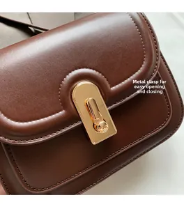 Gros plan d'un sac à main en cuir marron foncé avec fermoir rotatif en métal doré