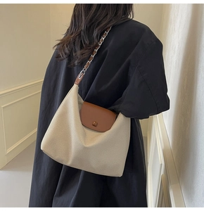 Detail of off-white canvas tote with brown leather flap and silver chain shoulder strap